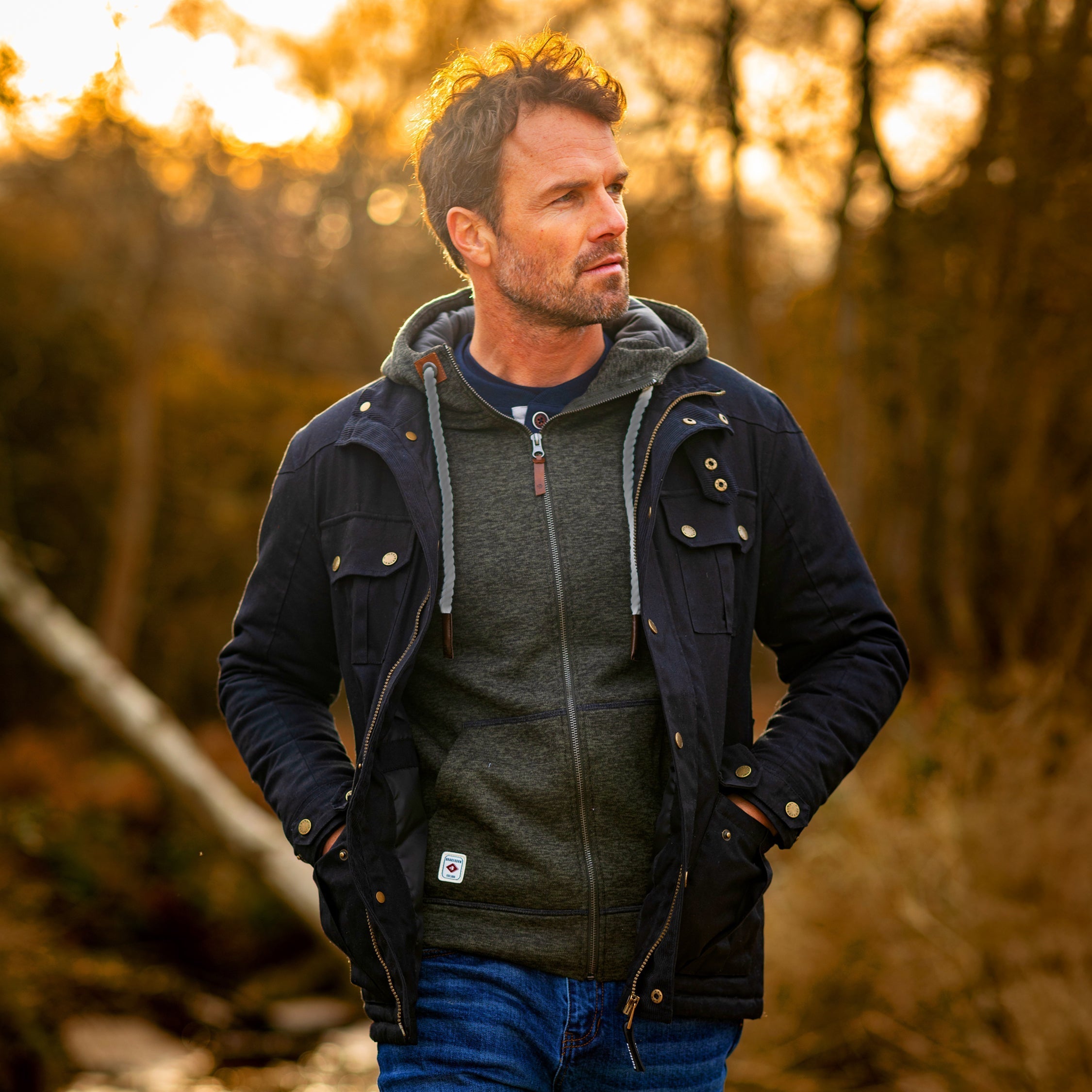 Model wearing a mens Brakeburn wax jacket walking along a forest path.