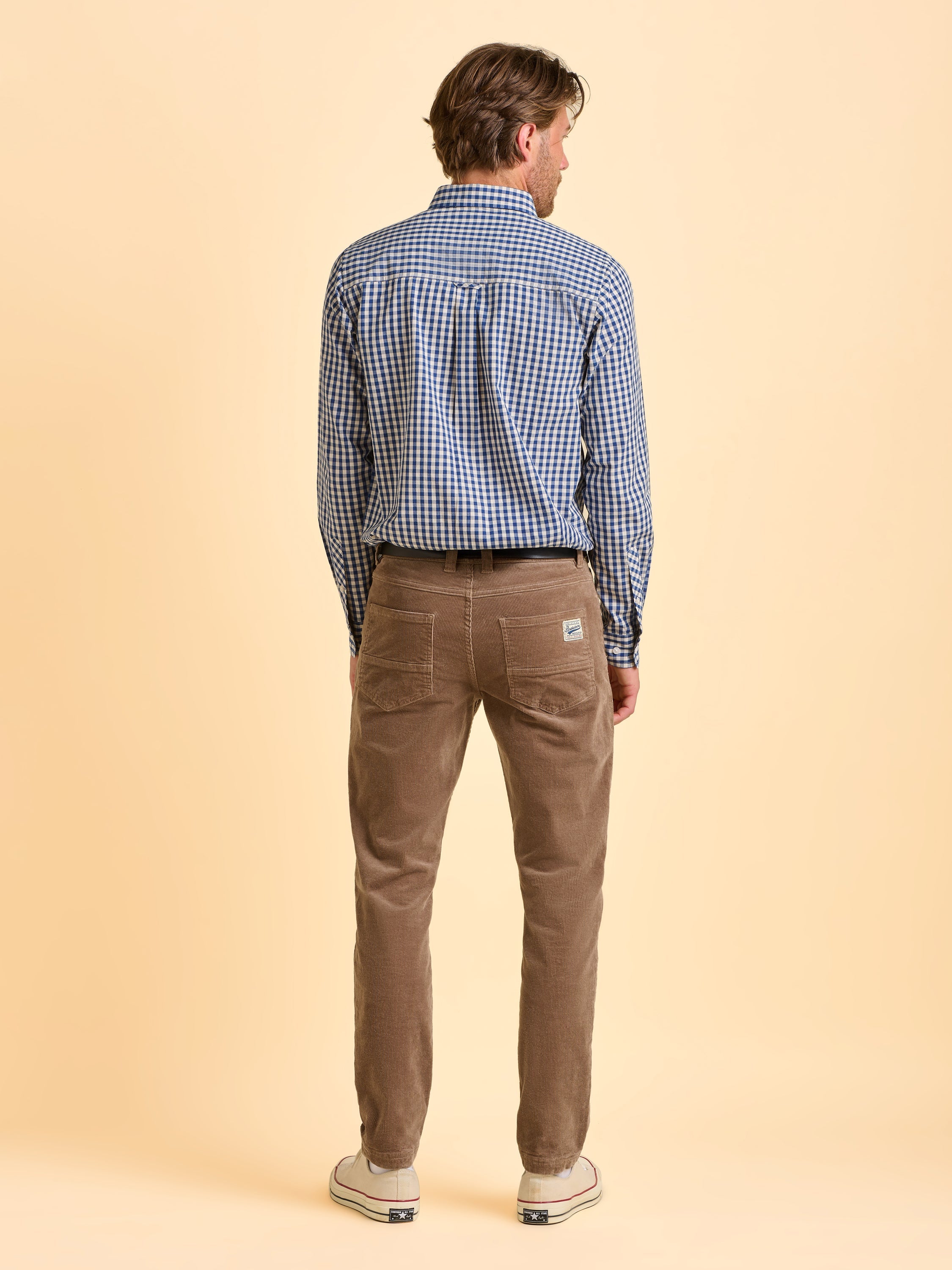 Male model wearing brown Brakeburn corduroy trousers facing the other way to show off the back of the trousers