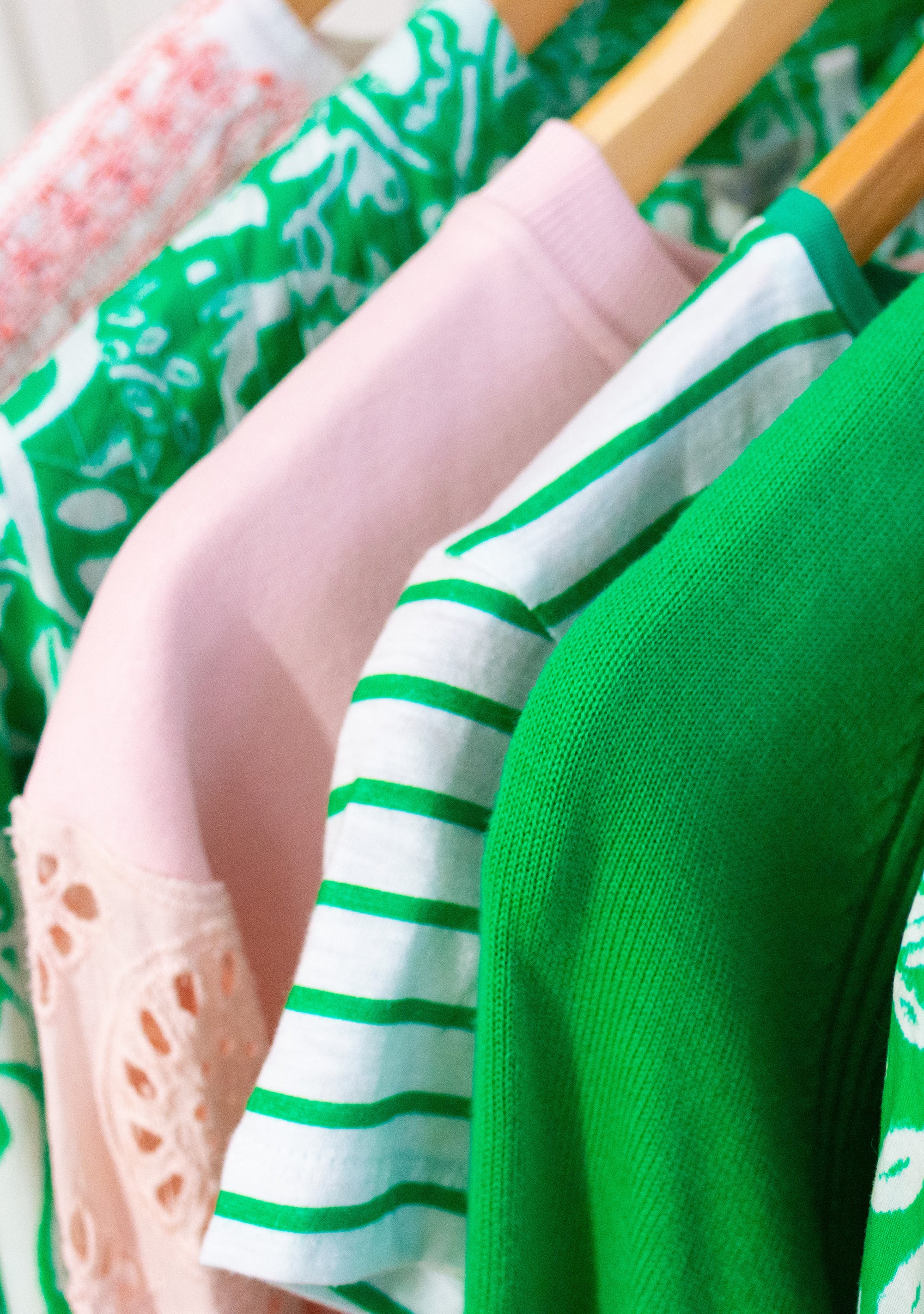 Close-up of colorful clothing on a rack with green, pink, and striped patterns.