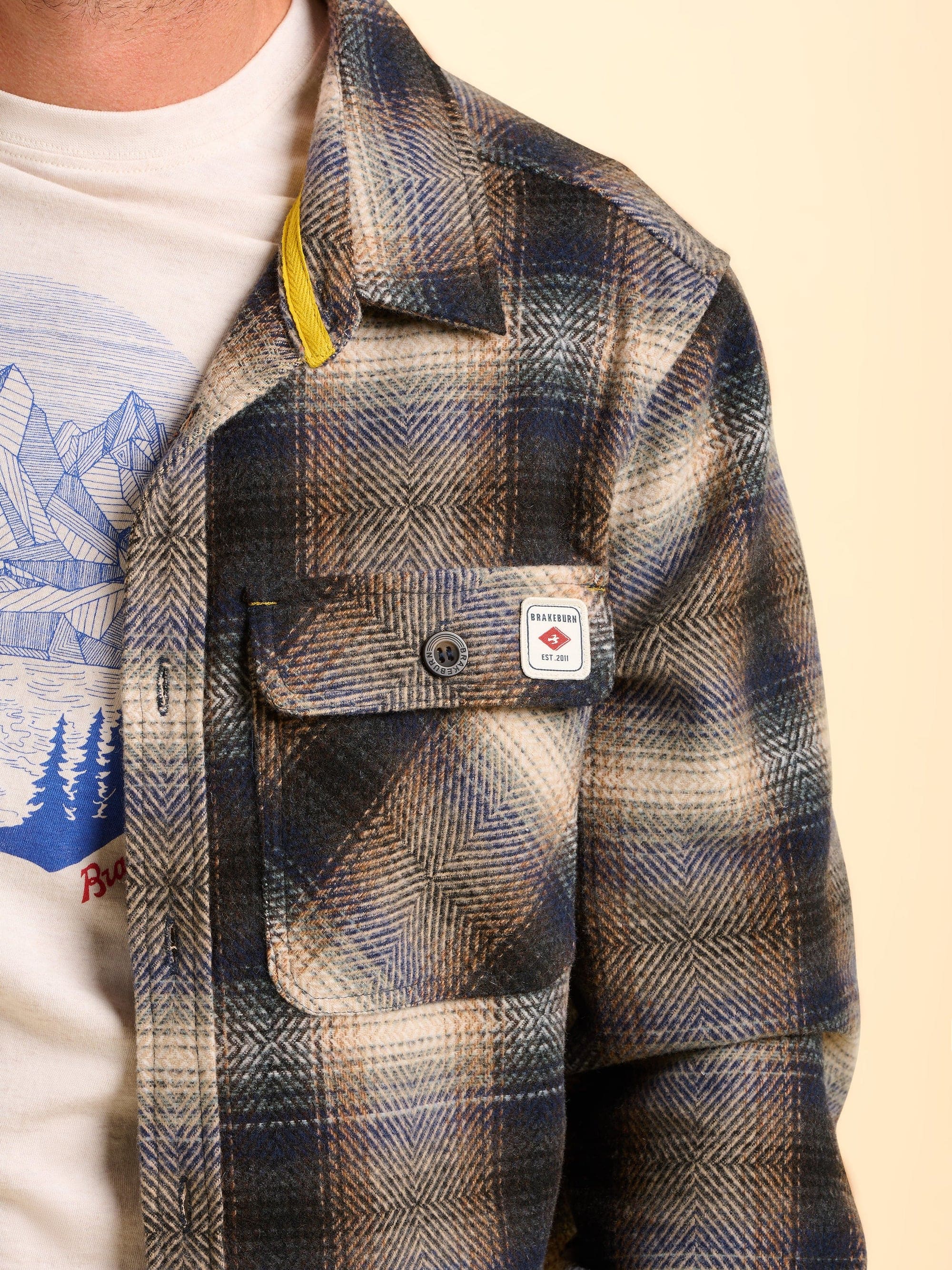 Brown plaid check jacket with a Brakeburn logo on the front pocket.