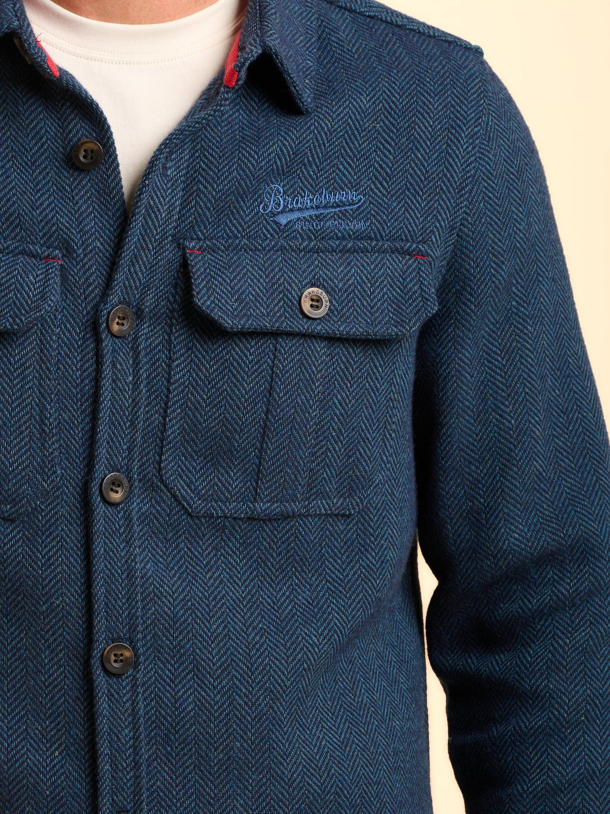 Blue textured jacket with a Brakeburn logo above the front pocket.
