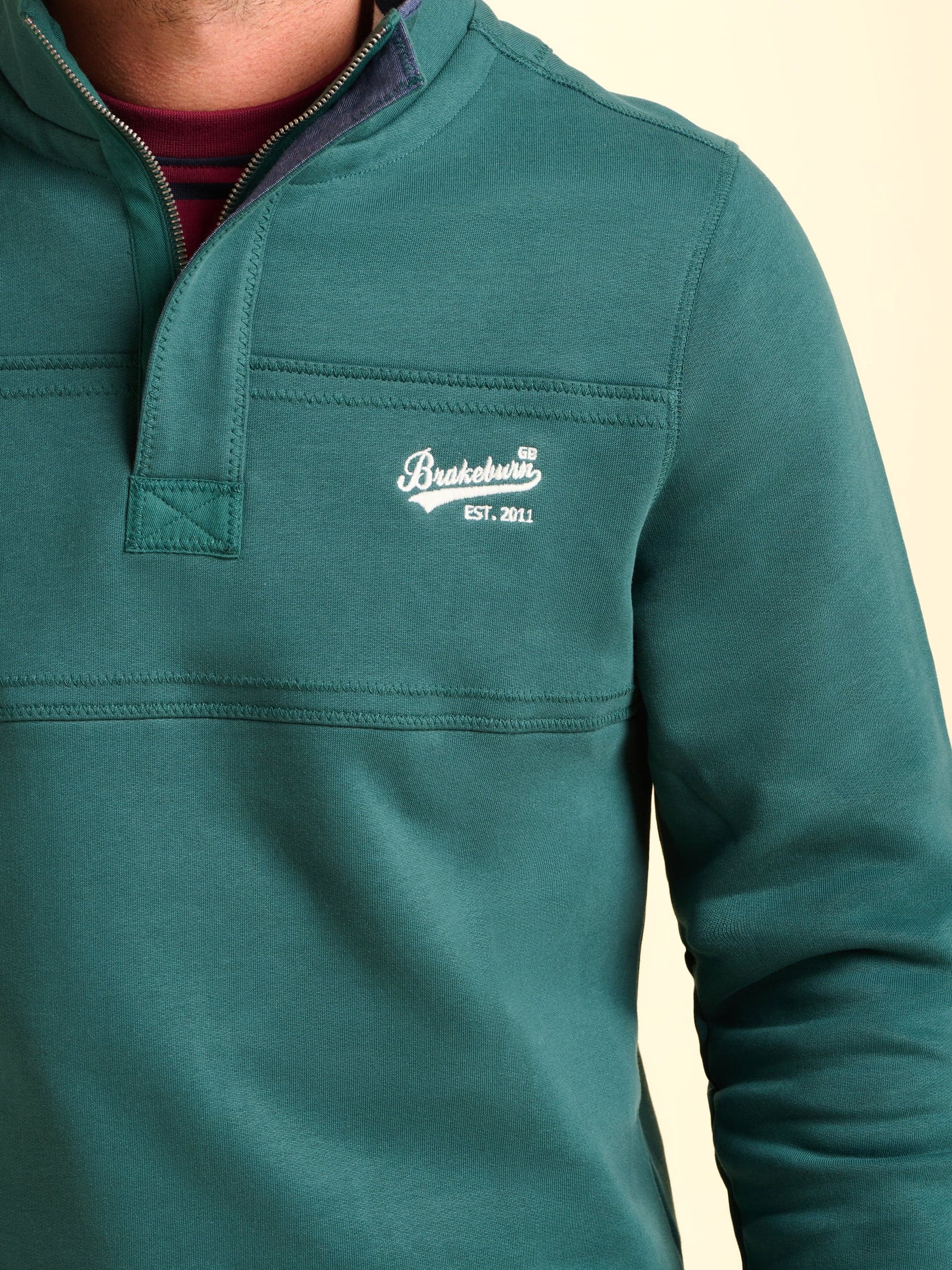 Teal pullover quarter zip with a Brakeburn logo embroidered in.