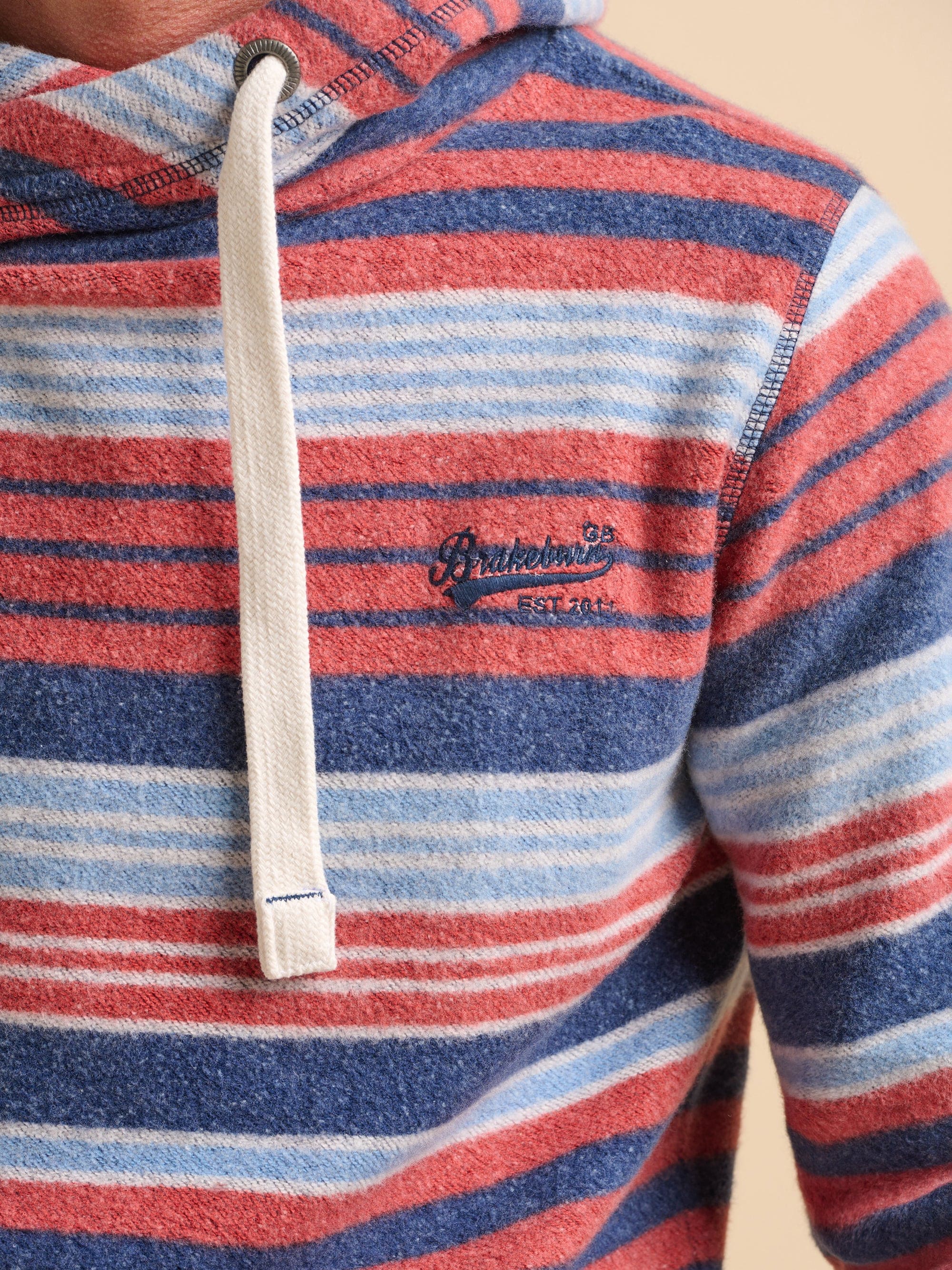Close-up of a striped hoodie with a Brakeburn logo on the front left.