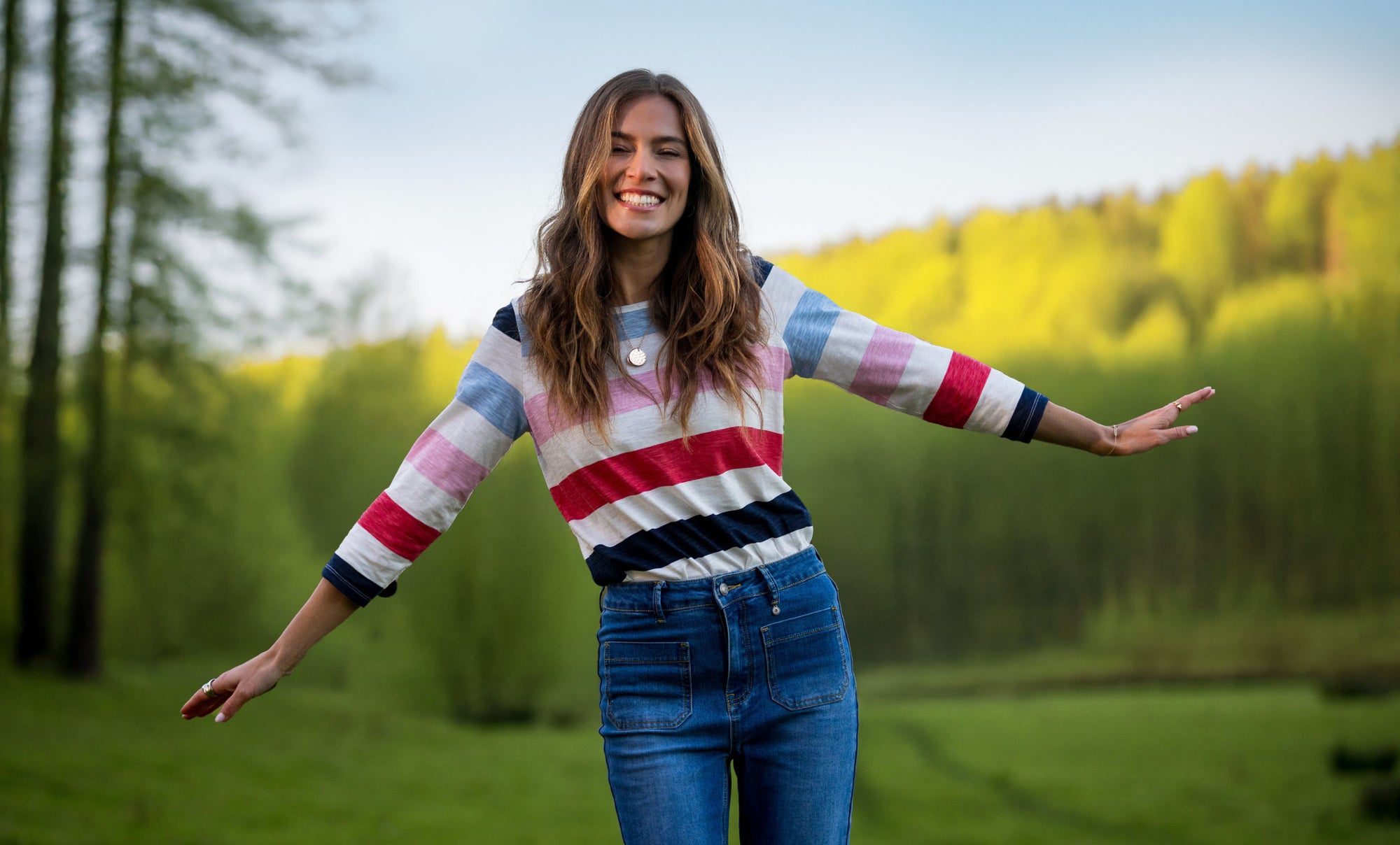 Women in a field wearing colourful top and denim jeans