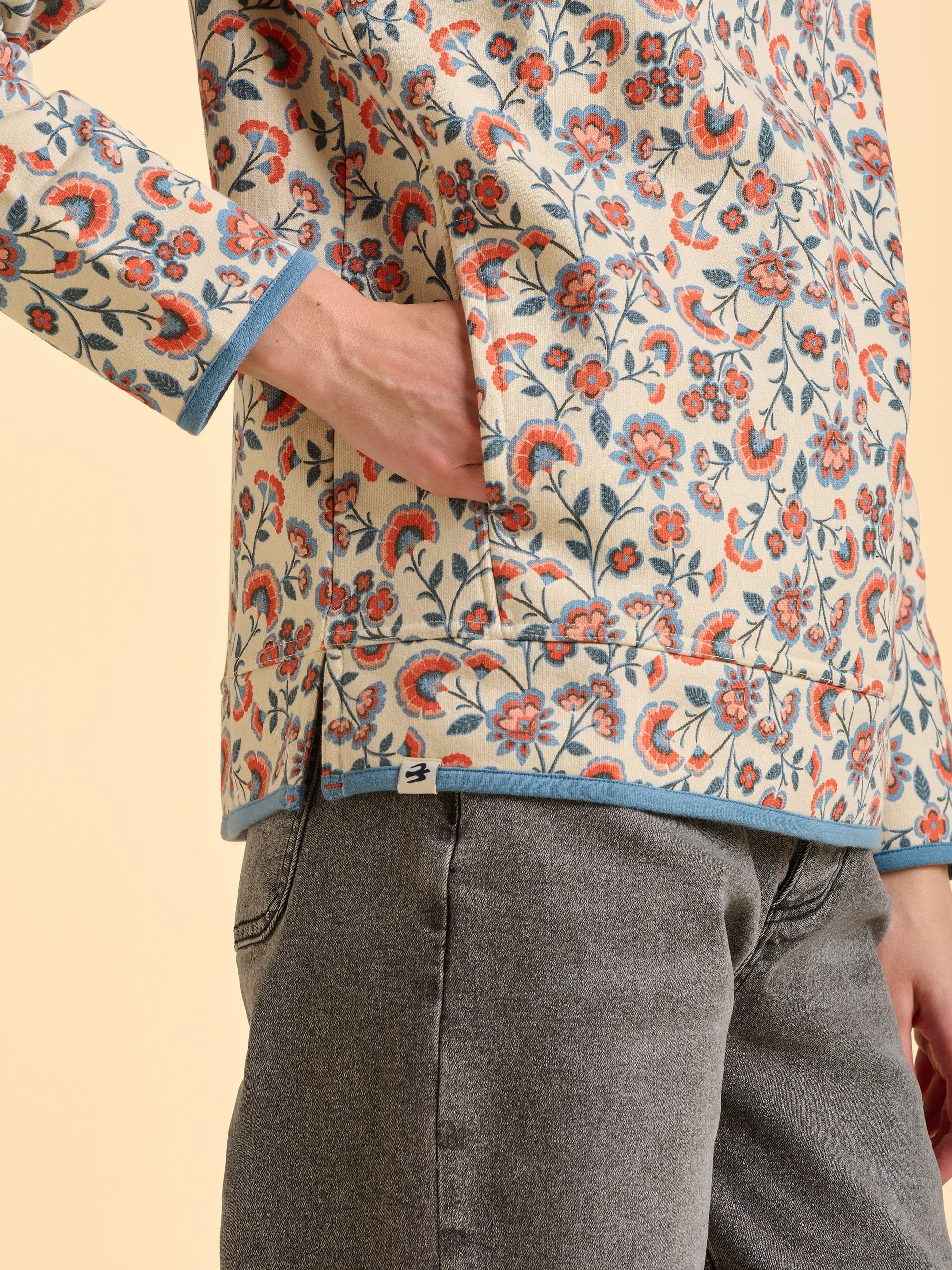 Women wearing the colehille floral patterned quarter zip in front of a beige background.