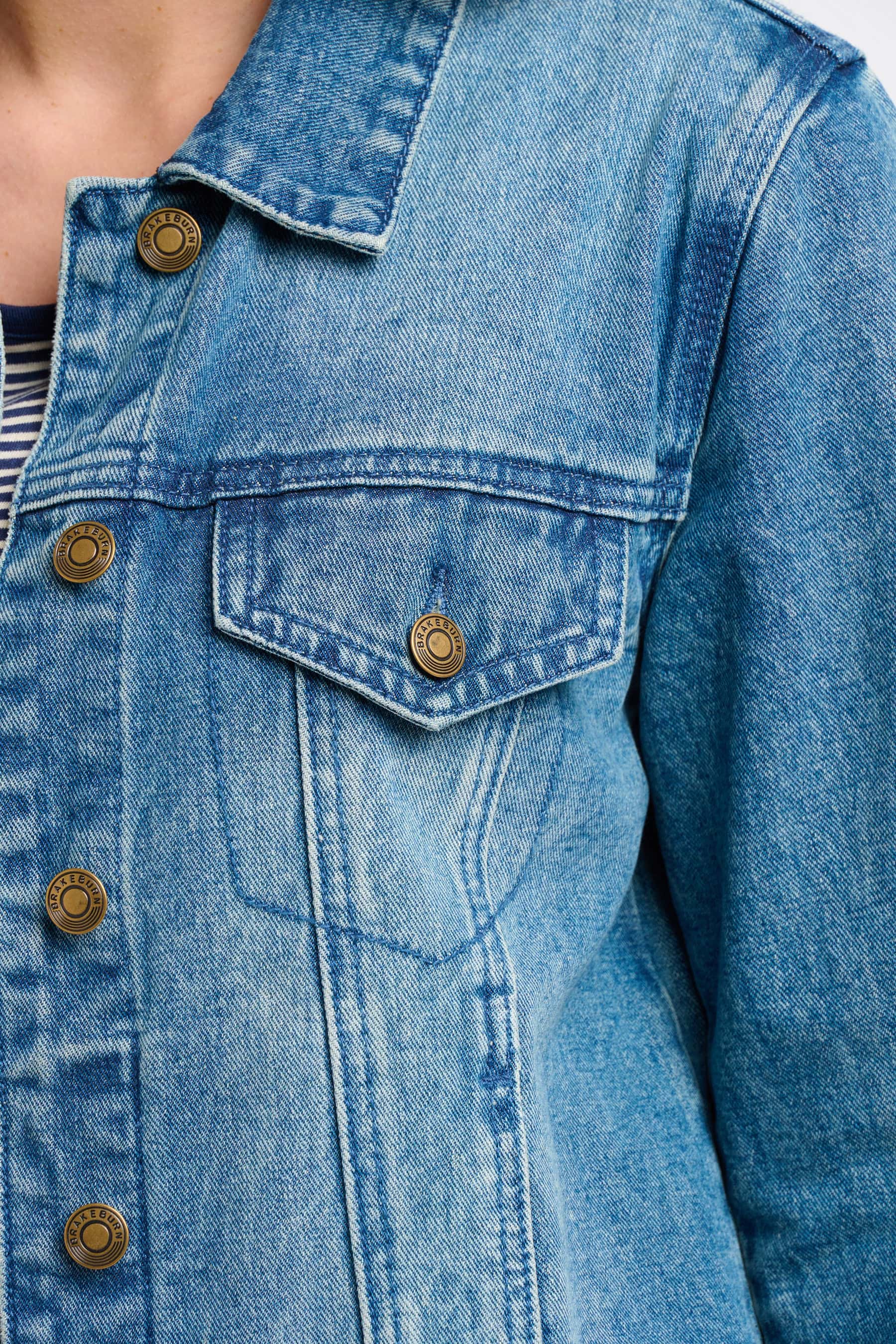 Close-up of a blue denim jacket with bronze buttons.